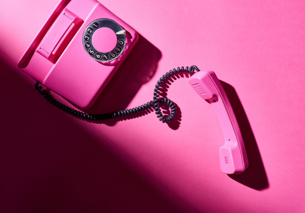 Top view of vintage pink telephone with shadow on bright surface